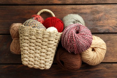 Soft woolen yarns on wooden table, flat lay