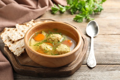 Bowl of Jewish matzoh balls soup on wooden table