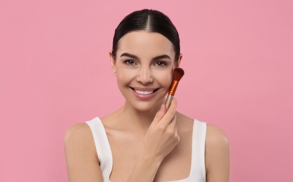 Photo of Beautiful woman applying makeup with brush on pink background. Space for text