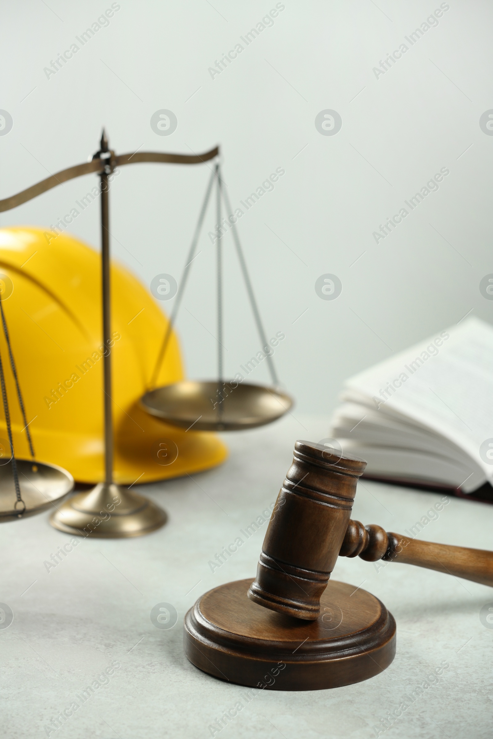Photo of Construction and land law concepts. Gavel, scales of justice and hard hat on white table indoors