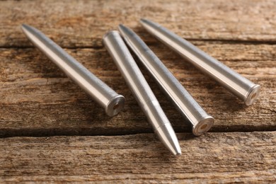 Photo of Many metal bullets on wooden table, closeup