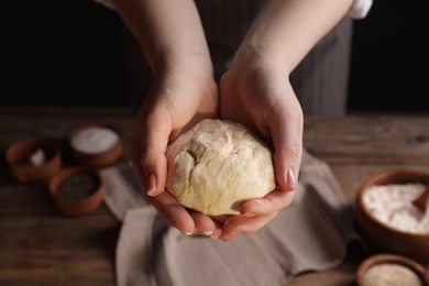 Woman with fresh dough at wooden table with ingredients, closeup. Cooking traditional grissini