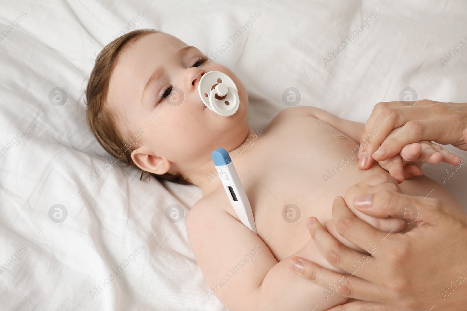 Photo of Mother measuring her baby's temperature, closeup. Health care