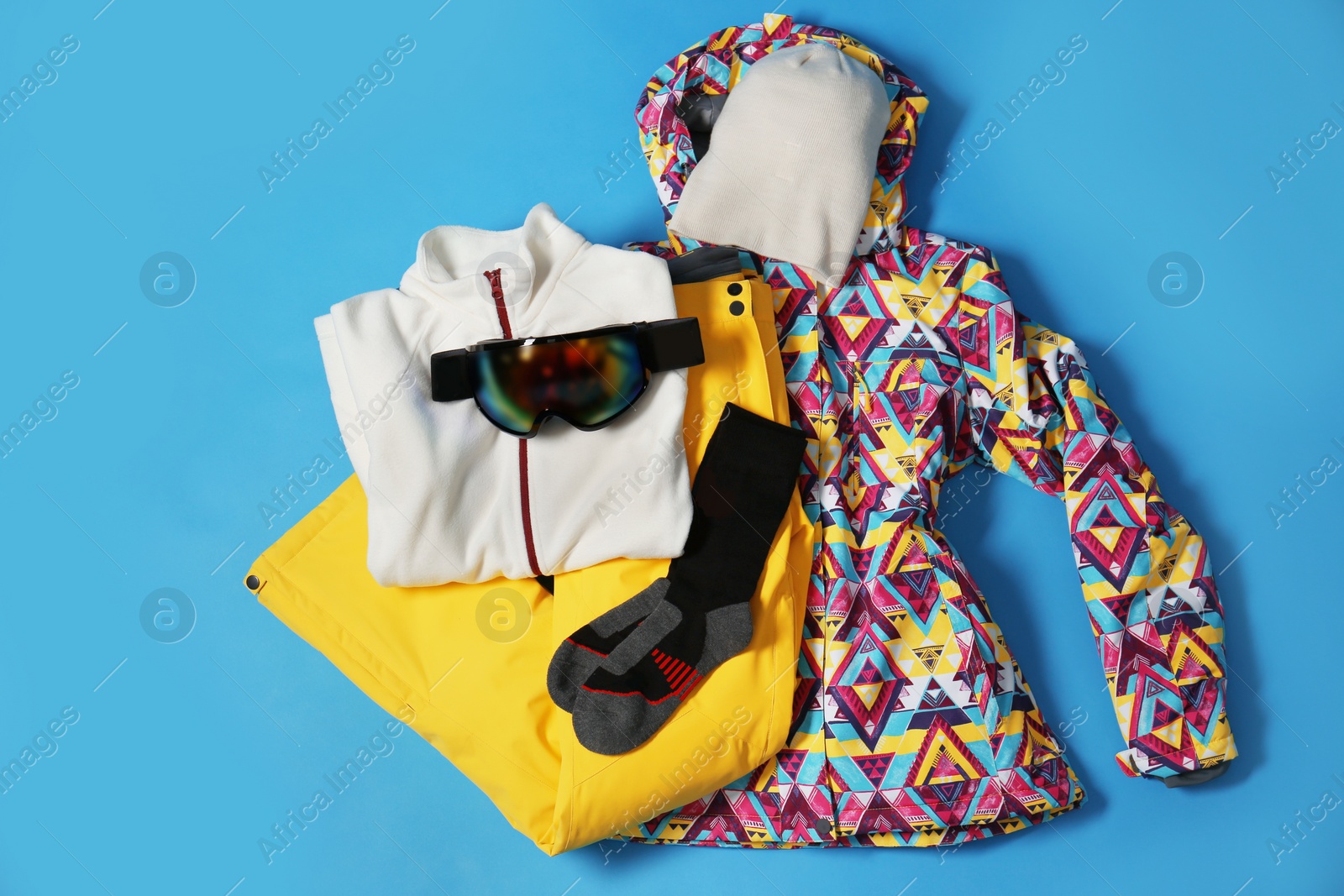 Photo of Stylish winter sport clothes on light blue background, flat lay