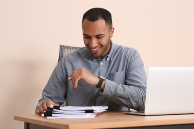 Happy businessman working with documents at wooden table in office