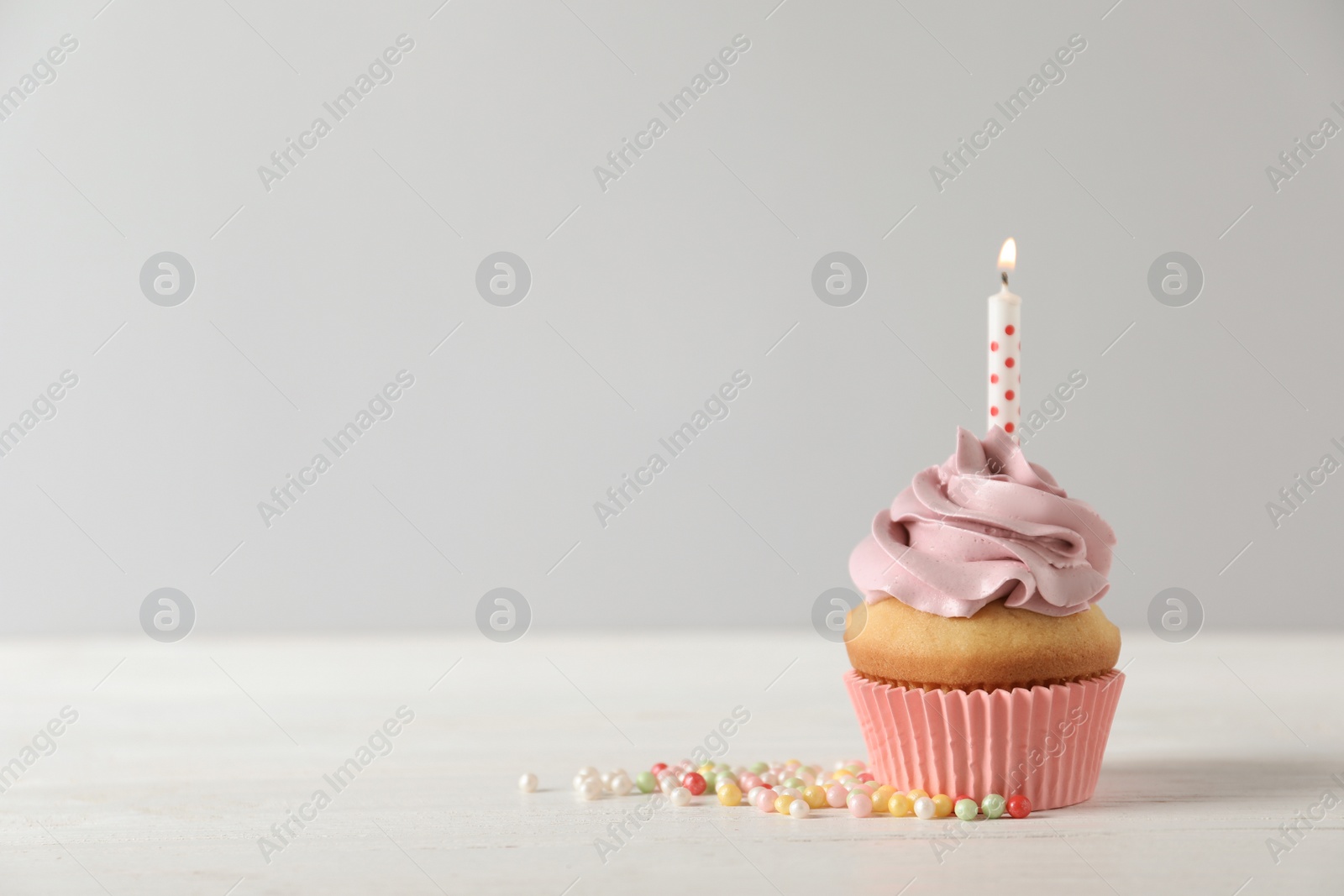 Photo of Delicious birthday cupcake with burning candle and space for text on light background