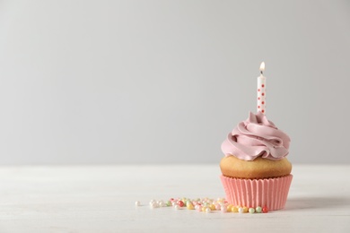 Photo of Delicious birthday cupcake with burning candle and space for text on light background