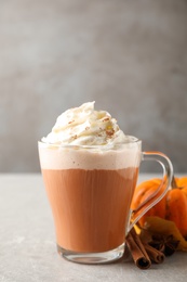 Photo of Delicious pumpkin latte on grey table, closeup
