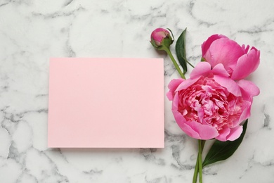 Photo of Fragrant peonies and blank card on marble table, top view with space for text. Beautiful spring flowers