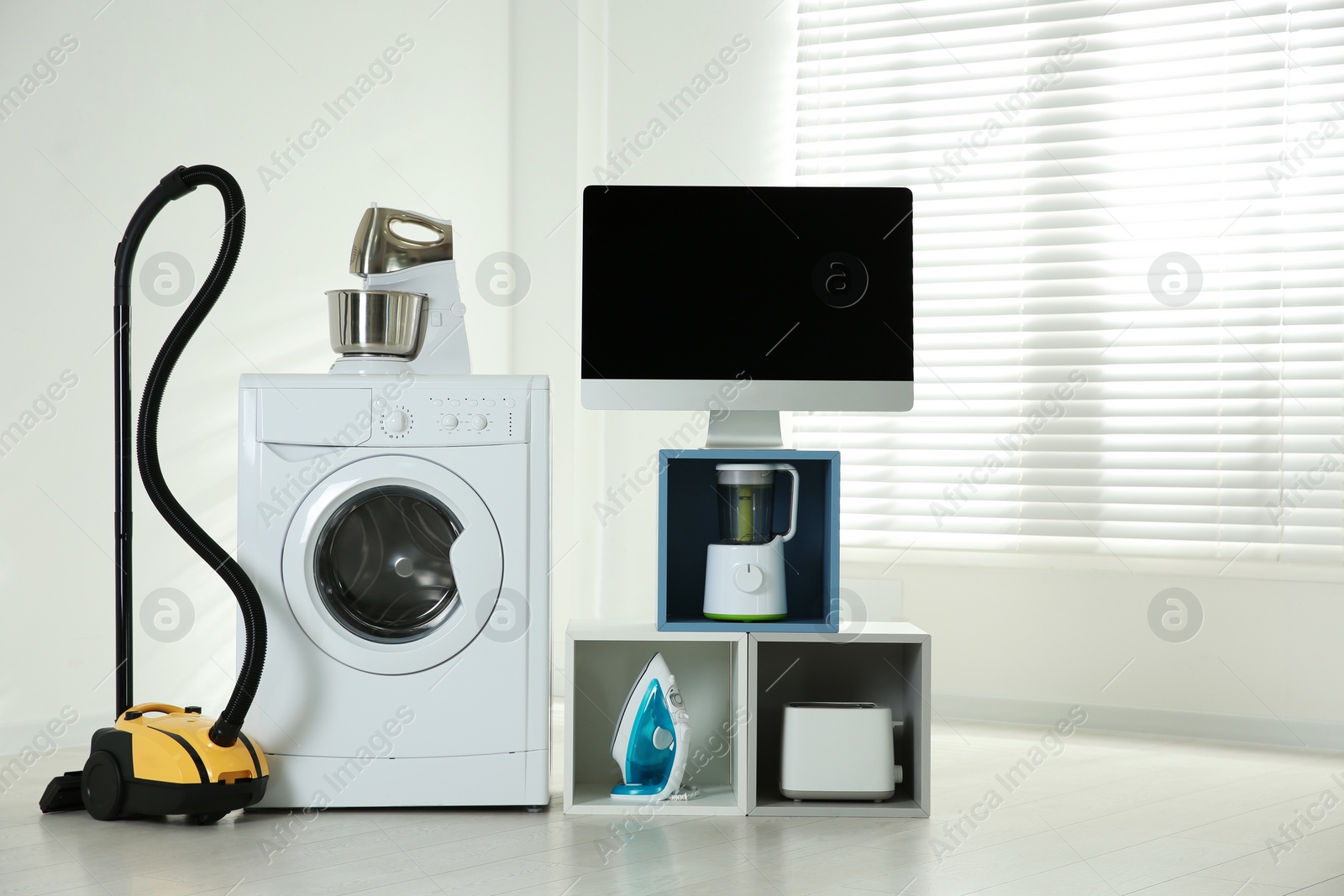 Photo of Modern vacuum cleaner and different household appliances near window indoors