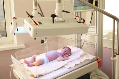 Photo of Newborn child under ultraviolet lamps in hospital
