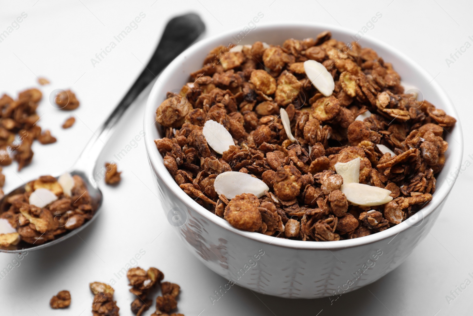 Photo of Bowl of tasty granola with nuts and dry fruits on white marble table