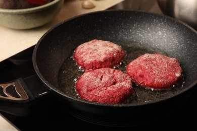 Cooking vegan cutlets in frying pan on stove, closeup