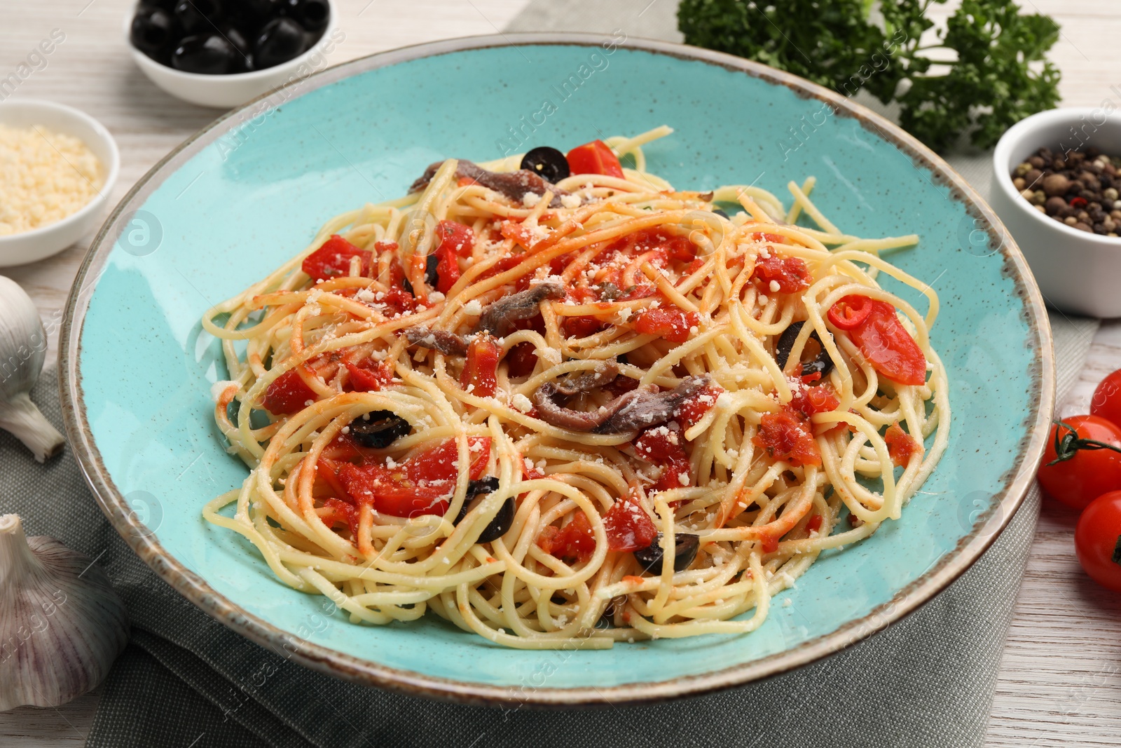 Photo of Delicious pasta with anchovies, tomatoes and parmesan cheese on table, closeup