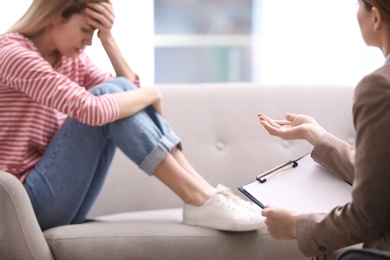 Photo of Psychotherapist working with young woman in light office