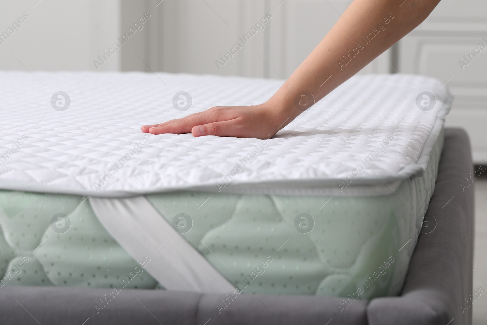 Photo of Woman touching new soft mattress in bedroom, closeup