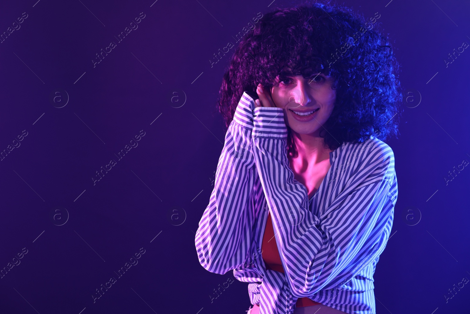 Photo of Beautiful young woman posing on color background in neon lights. Space for text