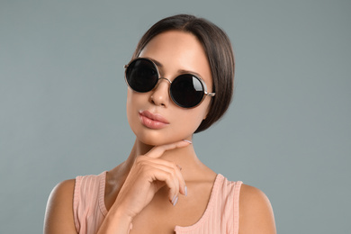 Photo of Beautiful young woman wearing sunglasses on grey background