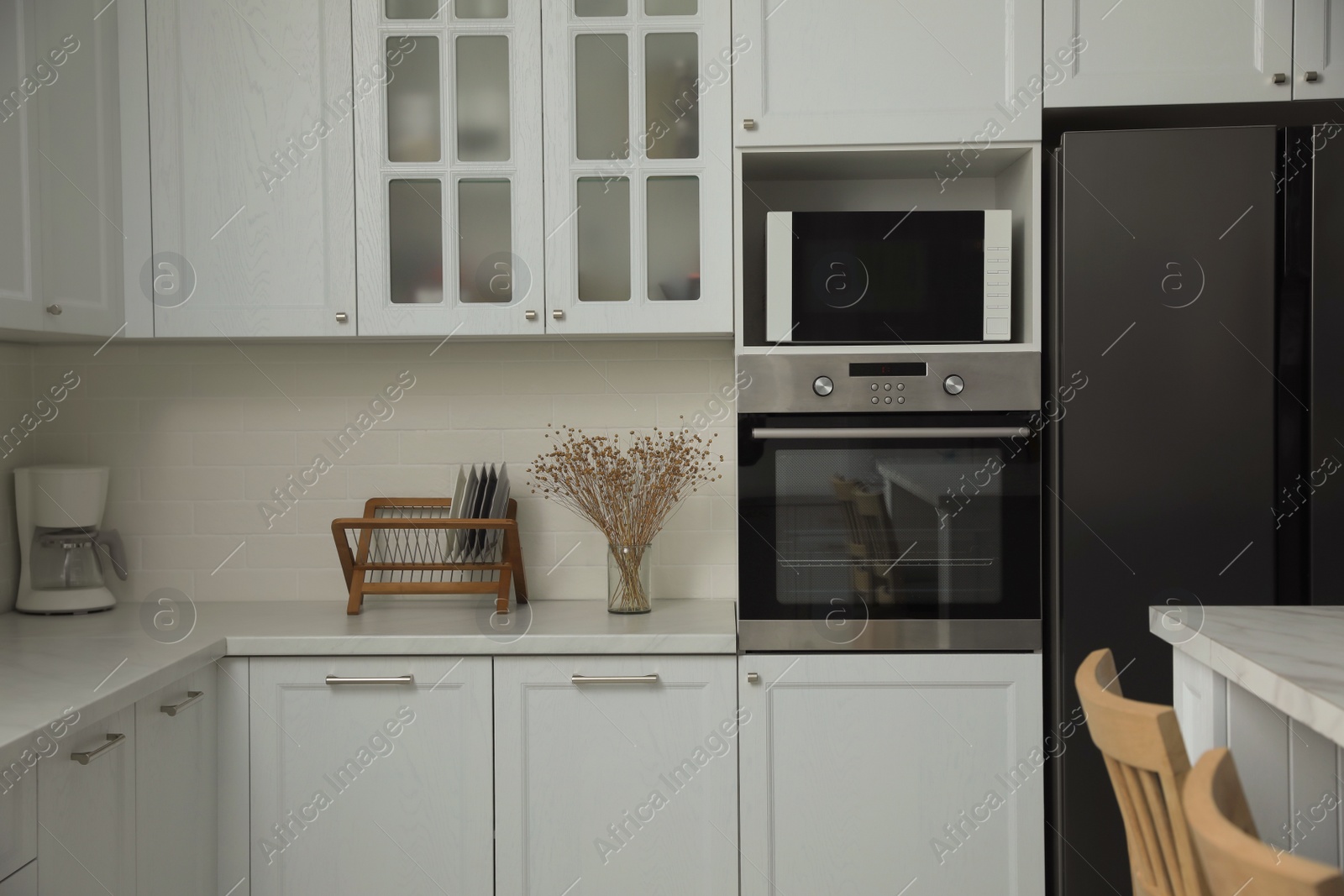 Photo of Modern microwave oven on shelf in kitchen