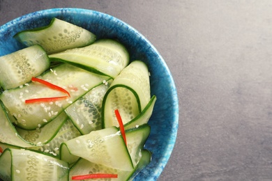 Photo of Dish with fresh cucumber salad on  table, top view. Space for text