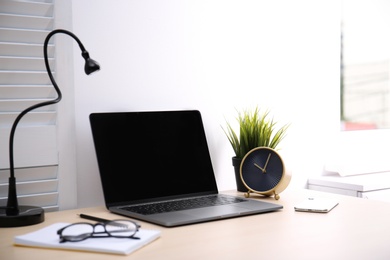 Photo of Modern workplace with laptop on table. Blank screen for mockup