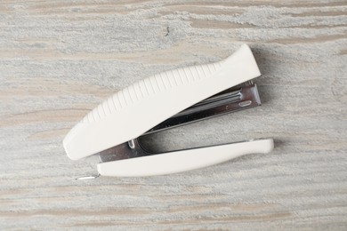 Photo of One white stapler on wooden table, top view