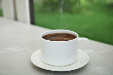 Photo of Cup of hot aromatic coffee on white wooden windowsill. Rainy weather