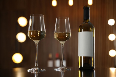 Photo of Bottle and glasses of wine on table against blurred background. Space for text
