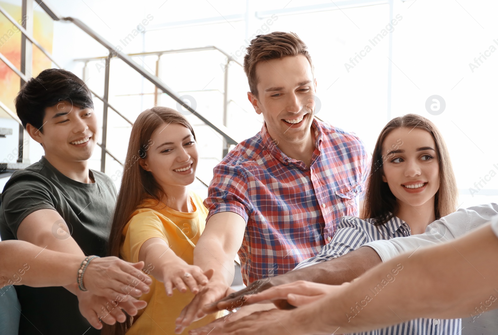 Photo of People putting hands together indoors. Unity concept