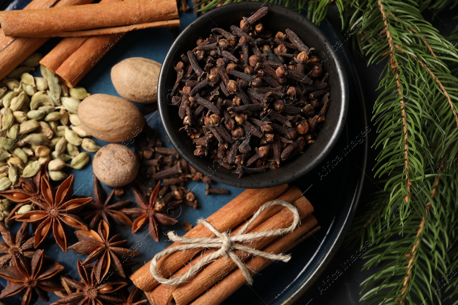 Photo of Dishware with different spices, nuts and fir branches on table, top view