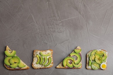 Photo of Tasty avocado toasts on grey table, flat lay. Space for text