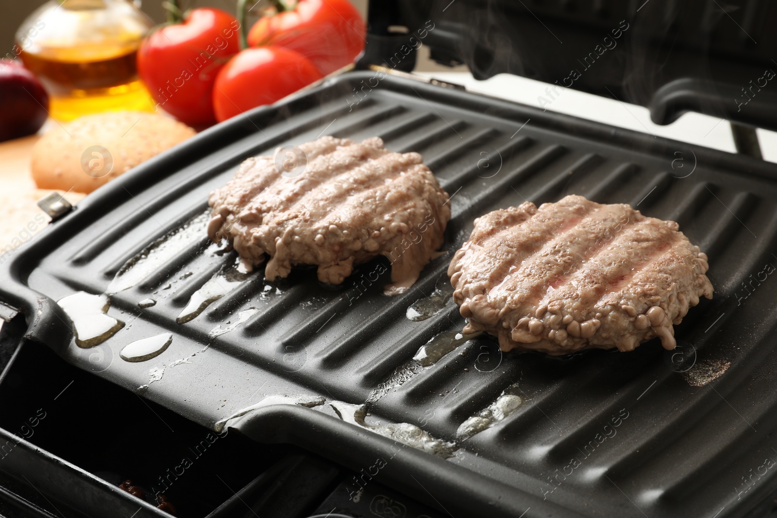 Photo of Delicious hamburger patties cooking on electric grill, closeup