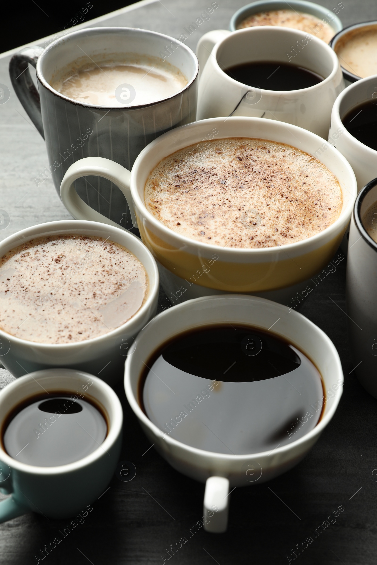 Photo of Many cups of different coffees on slate table