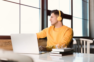 Photo of Man listening to audiobook at table in cafe