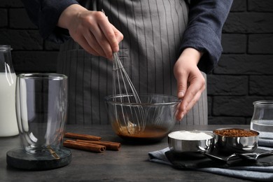 Photo of Woman whipping cream for dalgona coffee at grey table, closeup