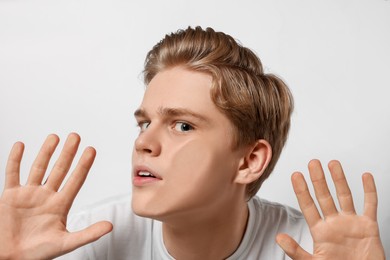 Photo of Shocked teenage boy stuck to transparent screen