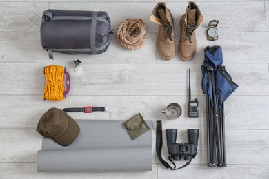 Flat lay composition with sleeping bag and camping equipment on wooden background. Space for text
