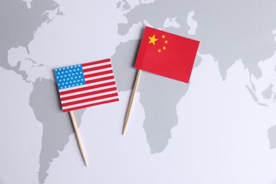 Photo of American and Chinese flags on world map, top view. Trade war concept