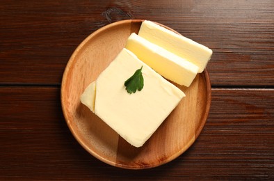 Photo of Cut tasty butter on wooden table, top view