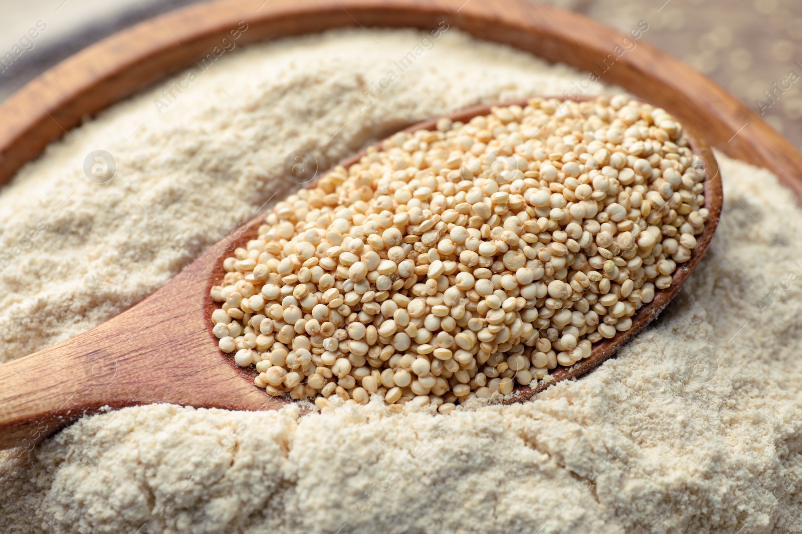 Photo of Wooden spoon with seeds on quinoa flour in bowl, closeup