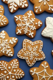 Photo of Tasty star shaped Christmas cookies with icing on blue background, flat lay