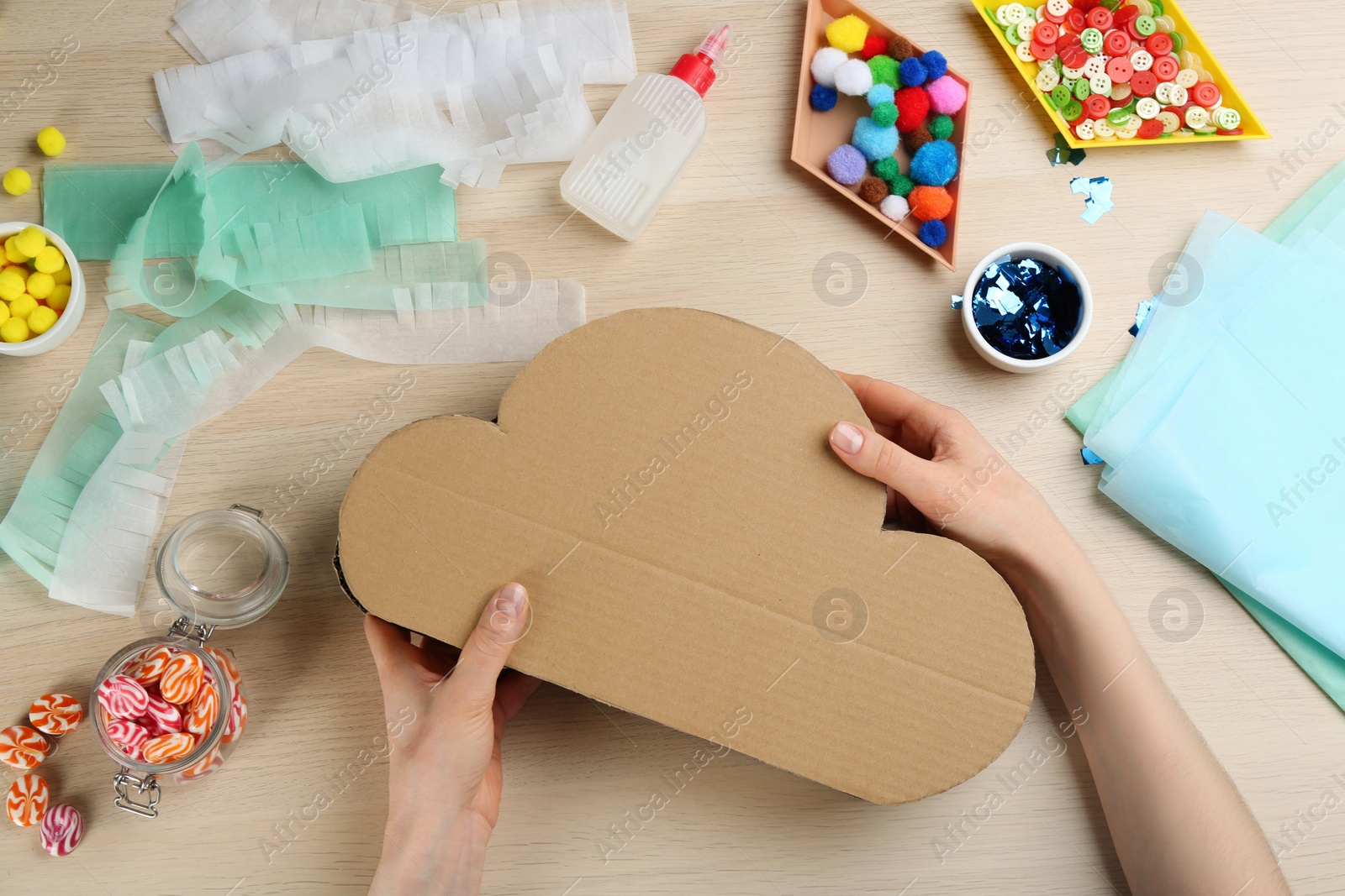 Photo of Woman making cardboard cloud at wooden table, top view. Pinata diy