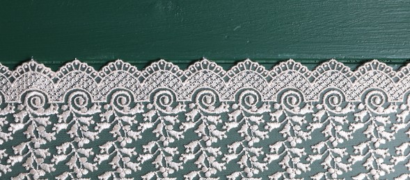 Photo of Beige lace on green wooden table, top view