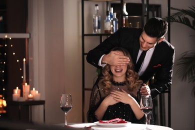 Man surprising his girlfriend in restaurant at Valentine's day dinner