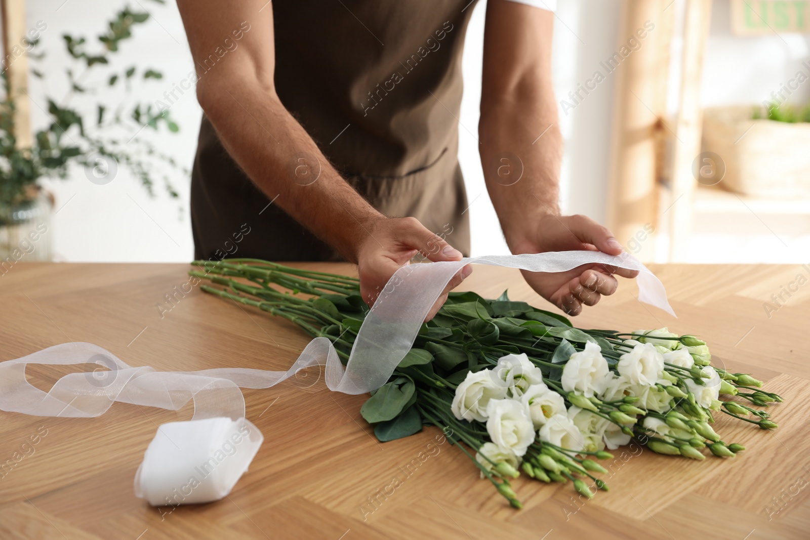 Photo of Florist making beautiful bouquet at table in workshop, closeup