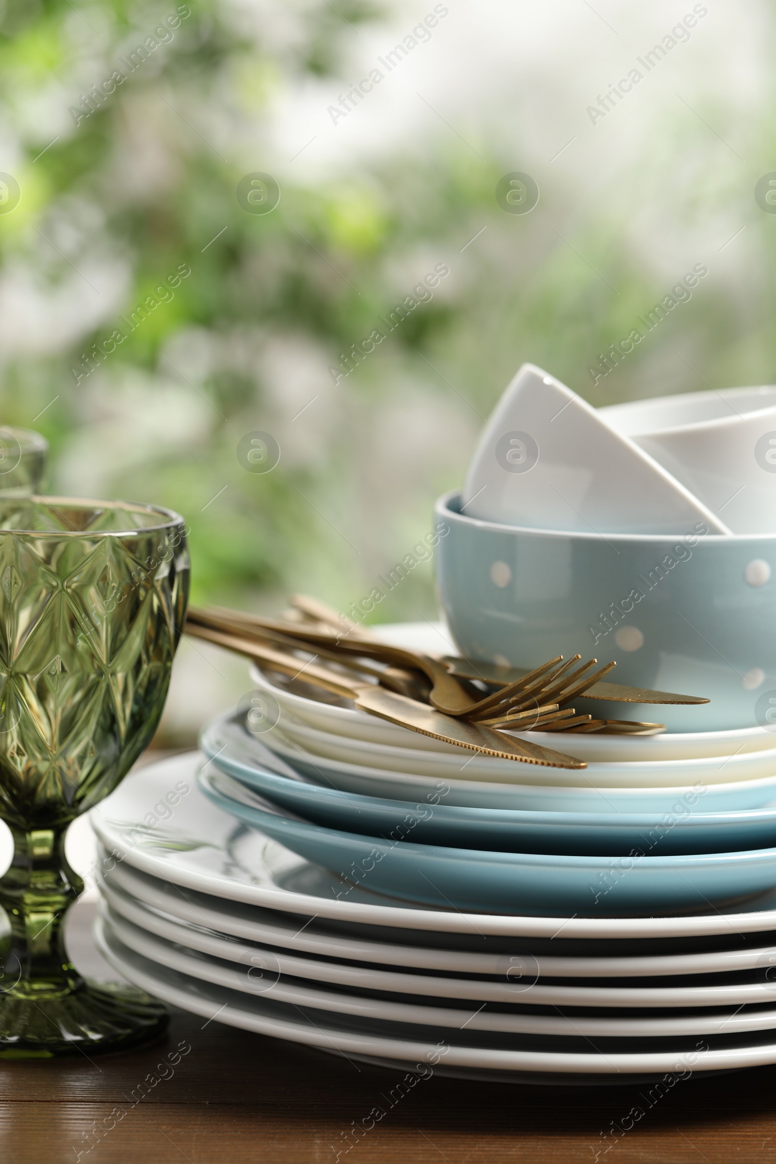 Photo of Beautiful ceramic dishware, glass and cutlery on wooden table outdoors