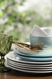 Beautiful ceramic dishware, glass and cutlery on wooden table outdoors