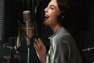 Photo of Young singer with microphone recording song in studio