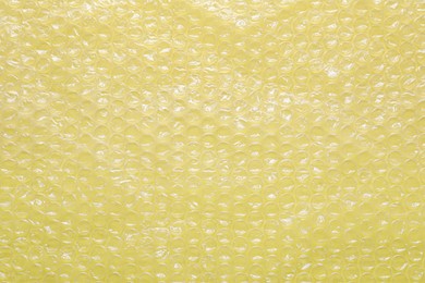 Photo of Transparent bubble wrap on yellow background, top view