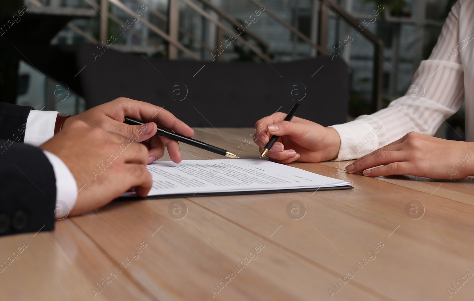 Photo of Businesspeople working with contract at wooden table indoors, closeup